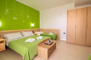 a bedroom with two beds and a green wall at Marini Hotel B&B in Lido Marini