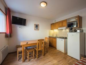 a small kitchen with a table and a refrigerator at Appartement confortable 2 Pièces Cabine 6 Personnes in Orcières