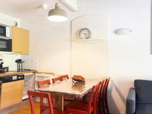 cocina con mesa con sillas y reloj en la pared en Résidence Pic Du Midi - 3 Pièces pour 7 Personnes 124, en La Mongie