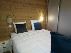 ein Schlafzimmer mit einem großen weißen Bett und einer Holzwand in der Unterkunft Résidence LUMI BATIMENT B - Appartement LUMI B pour 4 Personnes 754 in Valmorel