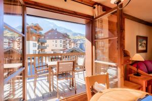 a room with a balcony with a table and chairs at Résidence Les Arcs Le Village - maeva Home - Appartement pièces - Prestige 134 in Bourg-Saint-Maurice