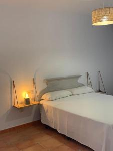 1 dormitorio con cama blanca y mesita de noche con lámpara en Cala Higuera, en El Pozo de los Frailes