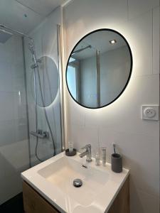 uma casa de banho com um lavatório e um chuveiro com um espelho. em Magnifique appart à 5 min des plages et commerces em Moliets-et-Maa