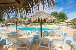 a group of chairs and umbrellas next to a swimming pool at Mobile home exotique Frejus in Fréjus