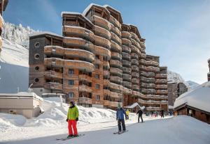 Résidence Arietis - Atria-Crozats - maeva Home - Appartement 3 pièces 7 pe 914 في مورزين: شخصان على زحليقة في الثلج أمام مبنى