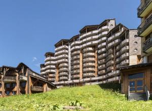 a tall apartment building with a green hill in front of it at Résidence Arietis - Atria-Crozats - maeva Home - Appartement 3 pièces 7 pe 914 in Morzine