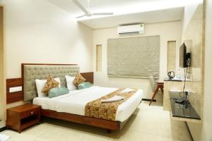 グルバルガにあるLUMBINIS GRAND HOTELのベッドとテレビのある寝室