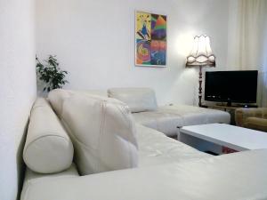 Apartment Beatris في سفيت: غرفة معيشة بأثاث أبيض وتلفزيون بشاشة مسطحة