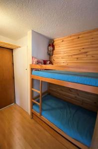 ein Schlafzimmer mit einem Etagenbett mit blauer Bettwäsche in der Unterkunft Résidence Airelles A - 2 Pièces pour 4 Personnes 424 in Risoul