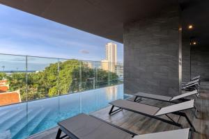 een balkon met 2 stoelen en een zwembad bij THE PANORA PATTAYA in Pattaya South
