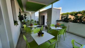 a patio with tables and green chairs on a balcony at Marini Hotel B&B in Lido Marini