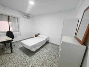 a white room with a bed and a desk and a chair at Piso completo en Calle Rafael in San Vicente del Raspeig