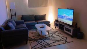 sala de estar con sofá y TV de pantalla plana en شقة بغرفه نوم وصالة, en Az Zulfi