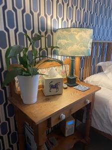 uma mesa com um vaso de planta ao lado de uma cama em No 12 em Lyme Regis