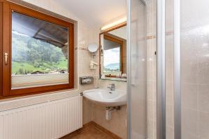 ein Bad mit einem Waschbecken und einem Fenster in der Unterkunft Hotel Bichlingerhof in Westendorf