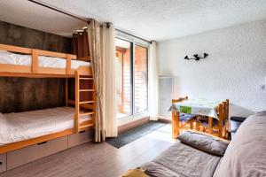 1 Schlafzimmer mit 2 Etagenbetten und einem Tisch in der Unterkunft Résidence Le Hameau - maeva Home - Studio 4 personnes - Sélection 854 in Vars