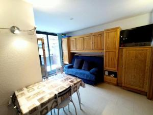 ein Wohnzimmer mit einem blauen Sofa und einem TV in der Unterkunft Résidence Relais - 2 Pièces pour 4 Personnes 114 in Réallon
