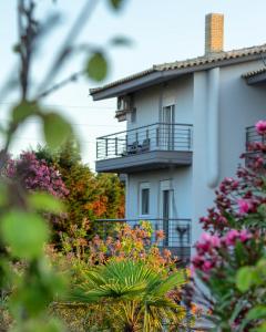 a white building with a balcony and some flowers at Villa Orama in Nea Potidaea