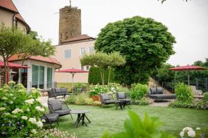 a garden with chairs and tables and umbrellas at Burghotel Staufeneck in Salach