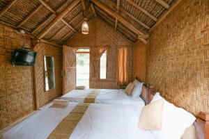 sypialnia z dużym białym łóżkiem w pokoju w obiekcie The Lavana Cici Bungalow Senggigi w mieście Senggigi