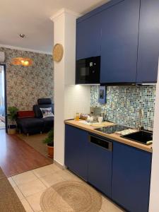 a kitchen with blue cabinets and a living room at Sóvirág Apartman in Egerszalók