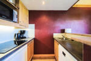 uma cozinha com uma parede vermelha e uma bancada em Quartier La Forêt - maeva Home - Appartement 3 pièces 5 personnes - Sélec 271 em Valmorel