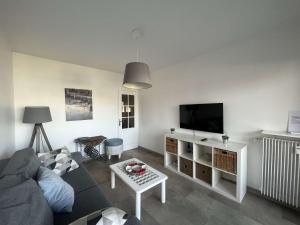een woonkamer met een bank en een flatscreen-tv bij Appartement 2 chambres, climatisation, vue mer, refait à neuf en 2020 in Saint-Mandrier-sur-Mer