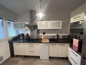 une cuisine avec des placards blancs et un comptoir noir dans l'établissement Appartement 2 chambres, climatisation, vue mer, refait à neuf en 2020, à Saint-Mandrier-sur-Mer