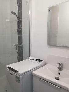 een witte badkamer met een wastafel en een spiegel bij Appartement 2 chambres, climatisation, vue mer, refait à neuf en 2020 in Saint-Mandrier-sur-Mer