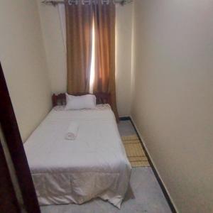 a small room with a bed and a window at consortium apartments in Bungoma
