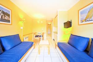 uma sala de estar com dois sofás azuis e uma mesa em Résidence le Hameau de Cap Esterel - maeva Home - Appartement 2 Pièces 5 Pe 11 em Saint-Raphaël