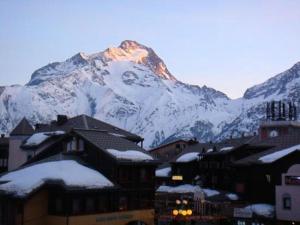 a snow covered mountain in front of a town with buildings at Résidence Ecrin - Pièces 944 in Vénosc