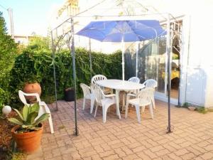 una mesa con sillas y una sombrilla azul en el patio en Bel appartement avec jardin à seulement 50 m de la plage et de Sanary.Climatisation, en Six-Fours-les-Plages