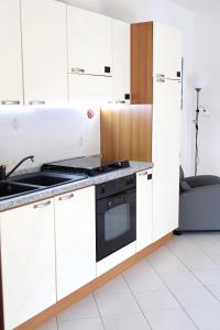 una cucina con armadietti bianchi e piano cottura di [Monza] Monolocale completo a Monza