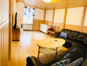 uma sala de estar com um sofá de couro preto e uma mesa em Lillstugan Sälen by em Sälen