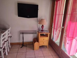 1 dormitorio con TV y mesa con lámpara en Chalets D Or - 2 Pièces pour 4 Personnes 164, en Vénosc