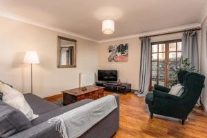 a living room with a couch and chairs and a television at Cromwell Corner - Donnini Apartments in Ayr