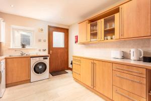a kitchen with wooden cabinets and a washer and dryer at Cromwell Corner - Donnini Apartments in Ayr