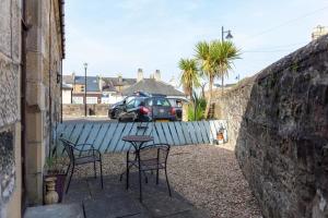 a patio with two chairs and a table and a car at Cromwell Corner - Donnini Apartments in Ayr