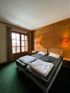two beds in a bedroom with a wooden wall at Résidence Alpina Lodge - 3 Pièces pour 6 Personnes 184 in Vénosc