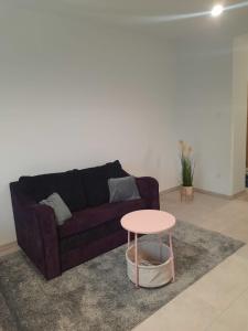 ein Wohnzimmer mit einem lila Sofa und einem rosa Tisch in der Unterkunft Studio Violet blisko rynku in Kalisz