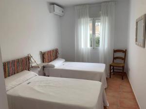 a room with three beds and a chair and a window at Cala San Pedro in El Pozo de los Frailes