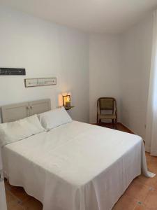 Cette chambre comprend un grand lit blanc et une chaise. dans l'établissement Cala San Pedro, à El Pozo de los Frailes