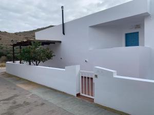 ein weißes Gebäude mit einem Zaun und einem Baum in der Unterkunft Cala San Pedro in El Pozo de los Frailes