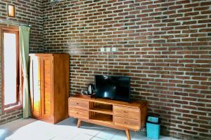 a television on a wooden dresser in front of a brick wall at Kampung Coklat Jembrana Mitra RedDoorz in Jembrana