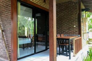 a glass door leading to a patio with a table at Kampung Coklat Jembrana Mitra RedDoorz in Jembrana