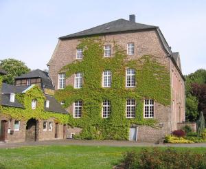 a large brick building covered in green ivy at Haus Overbach in Barmen