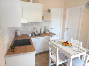 a kitchen with white cabinets and a table with a bowl of fruit at Villa Tina Country Beach Apartments in Acharavi