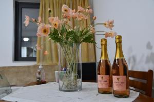 duas garrafas de vinho sentadas numa mesa com flores em Gina's Studio at Nafpaktos em Lepanto