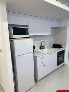 a white kitchen with a microwave and a refrigerator at דירת נופש משפחתית סי סייד אילת in Eilat